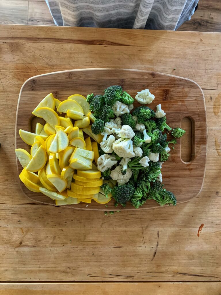 Chopped yellow squash, broccoli, and cauliflower on wooden cutting board