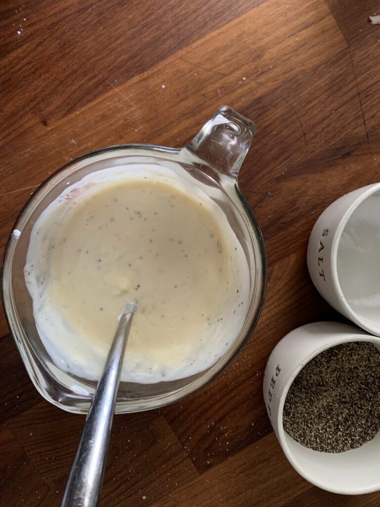 Pyrex glass measuring cup full of mayonnaise, greek yogurt, honey, salt and pepper