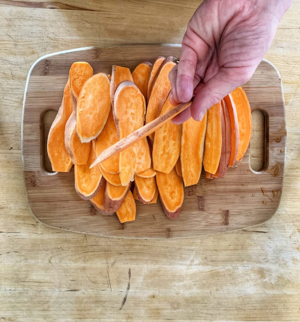 Sliced sweet potato on a wooden cutting board