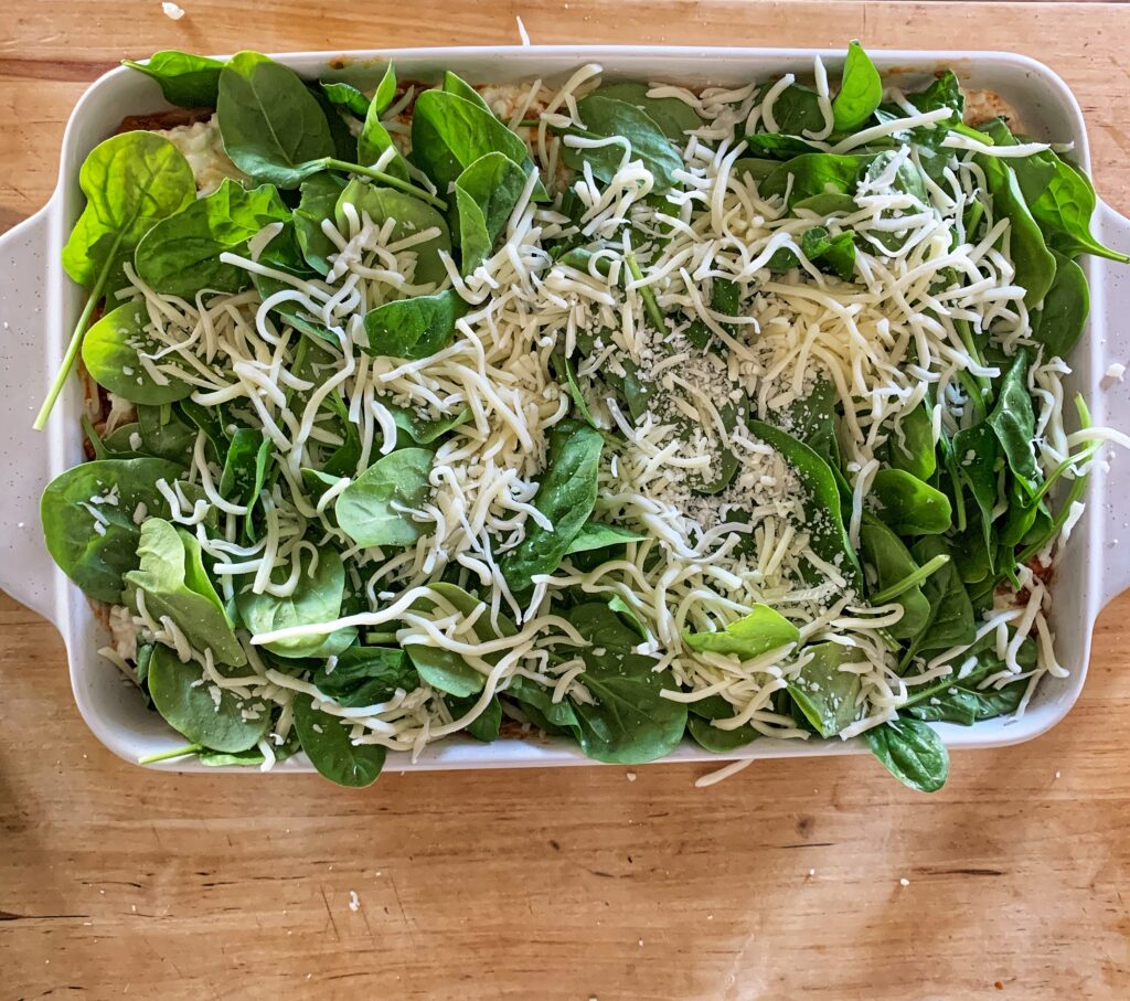 spinach and mozzarella topping sweet potato lasagna in white dish