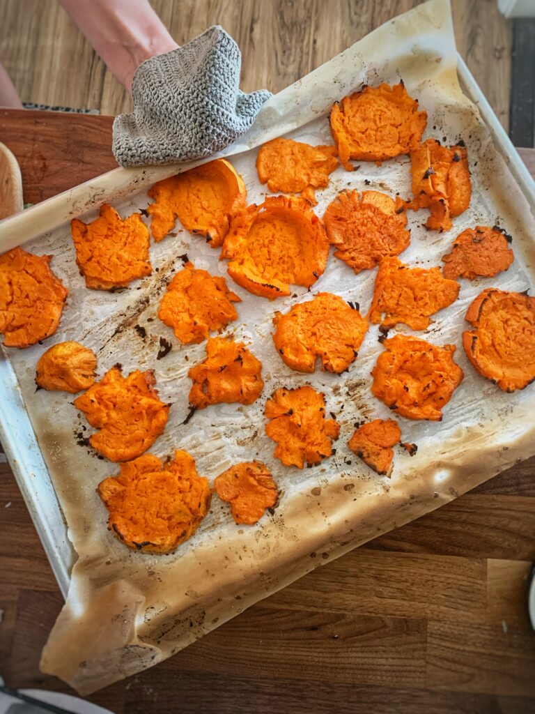 Smashed, roasted sweet potatoes on baking sheet