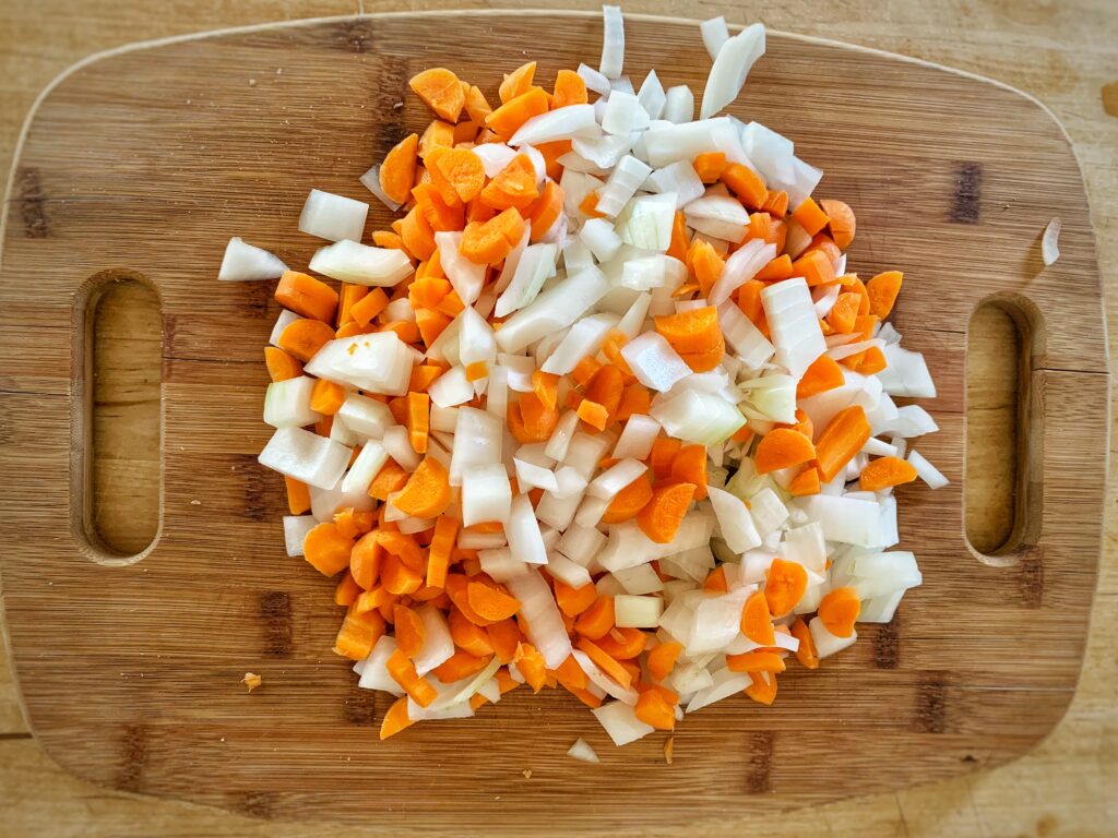 chopped carrots and onion on wooden cutting board