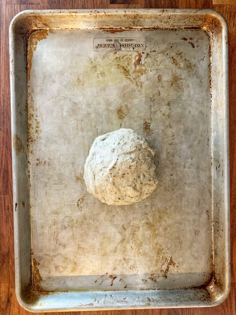 ball of pizza dough resting on cookie sheet