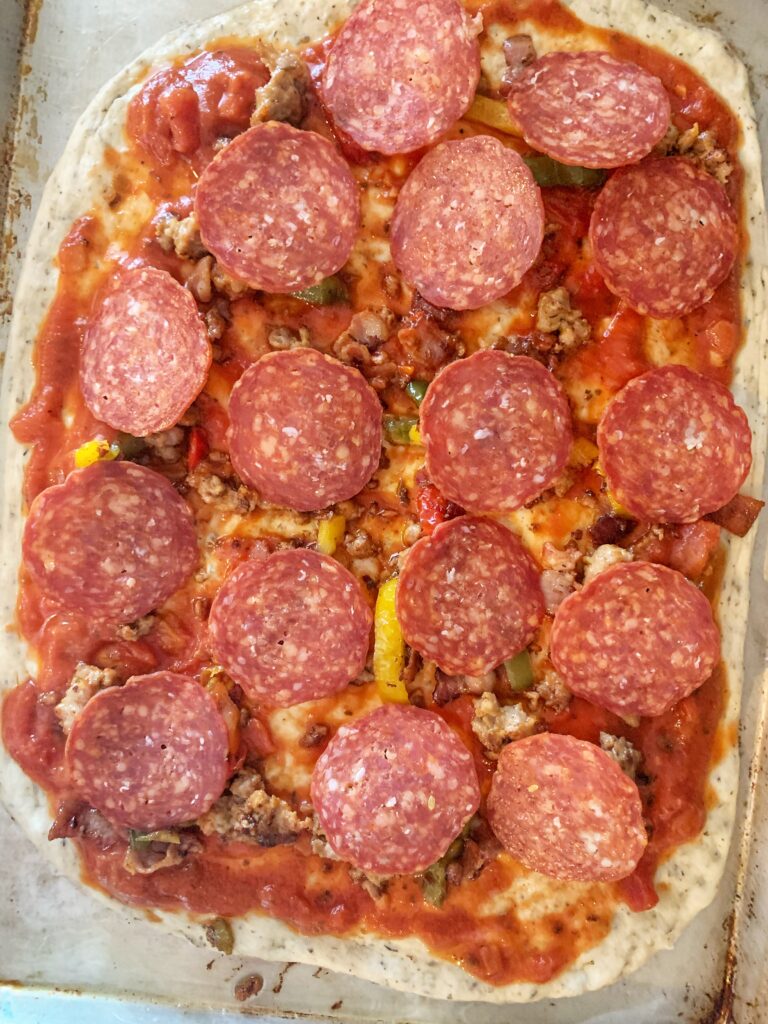 pepperoni on top of uncooked pizza