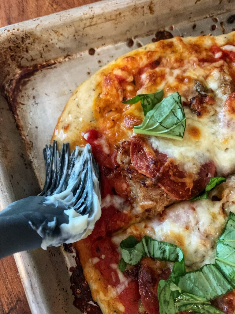 brushing pizza dough with butter