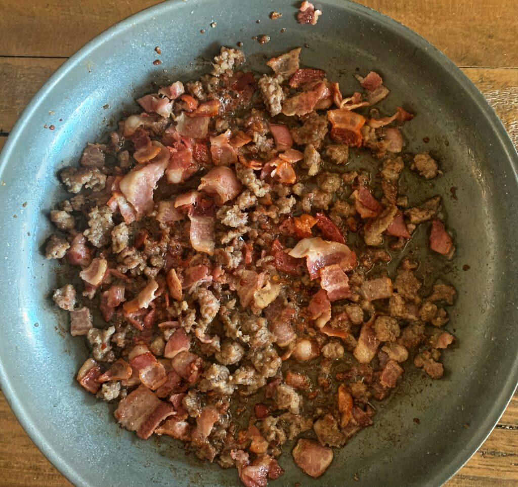 sausage and bacon cooking in skillet