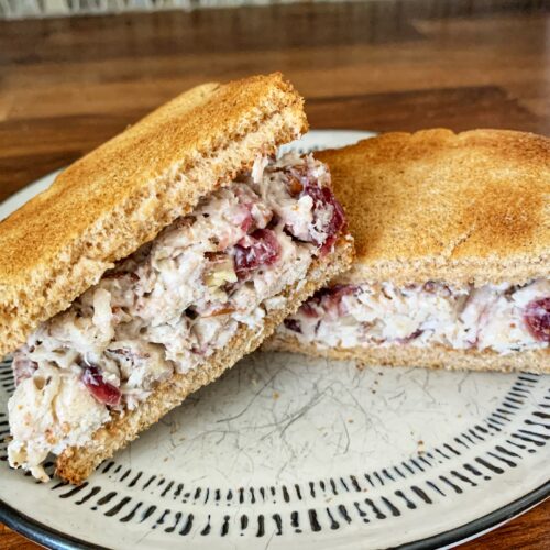 Chicken salad sandwich sliced in half stacked on plate