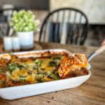 sweet potato lasagna on table in white dish with a serving on a spatula