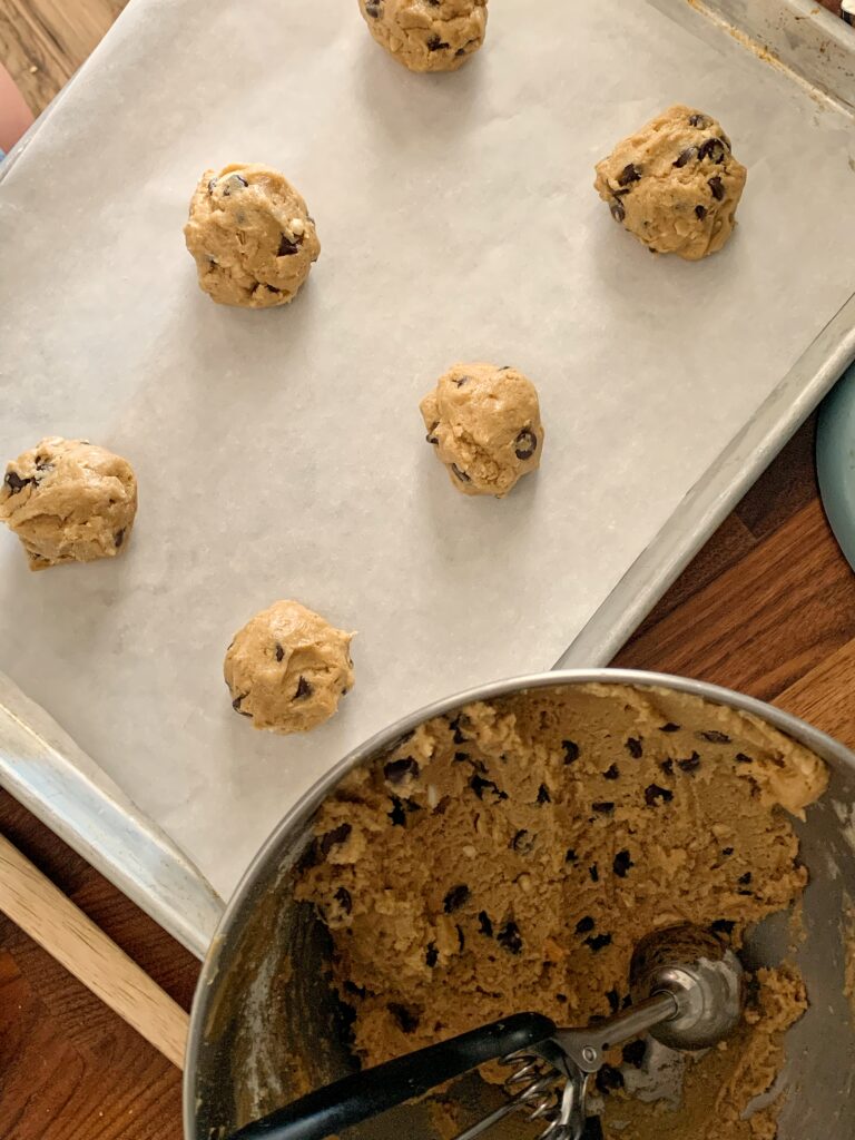 Cookie dough on cookie sheet next to bowl of dough