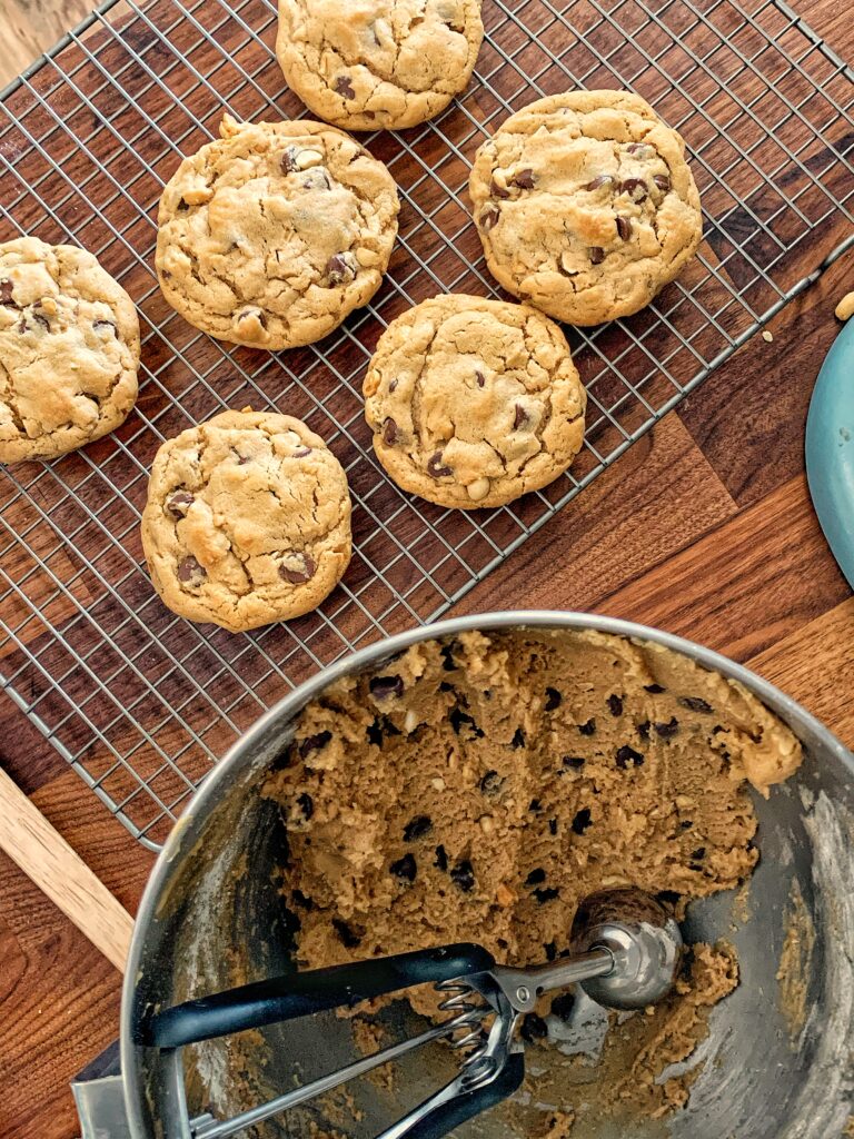 peanut butter chocolate chip cookies baked on cooling wrack next to bowl of dough